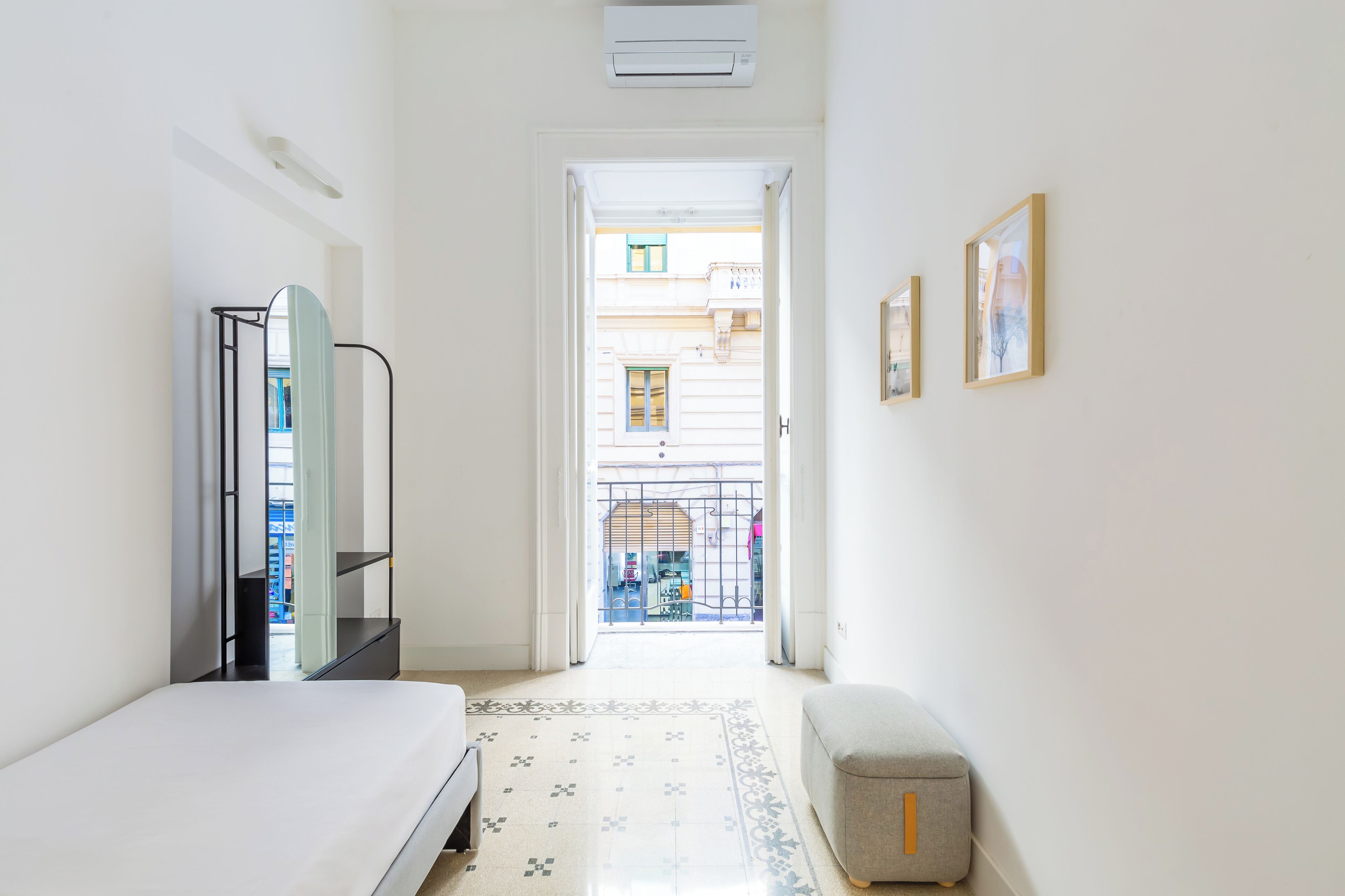 A narrow hallway leading to a balcony with a view of a building and a shop.