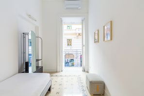 A narrow hallway leading to a balcony with a view of buildings.