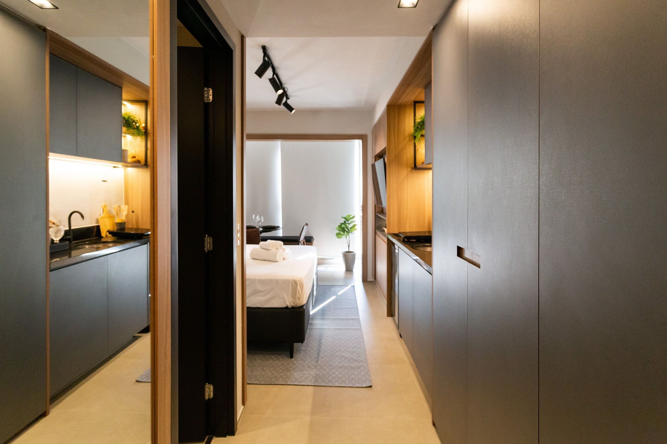A modern hotel room with a bed, bedside table, and a large mirror.