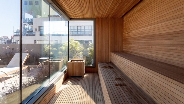 A modern interior with a wooden floor, a glass wall, and a view of the city.