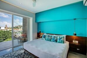A modern bedroom with a large bed, a view of the city, and a balcony.