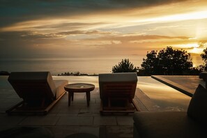 A sunset view from a terrace with two lounge chairs and a small table. - Olive Villas (West Mani)