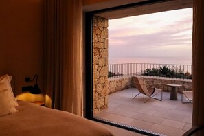 A balcony with a stone wall, a table, and two chairs. - Olive Villas (West Mani)