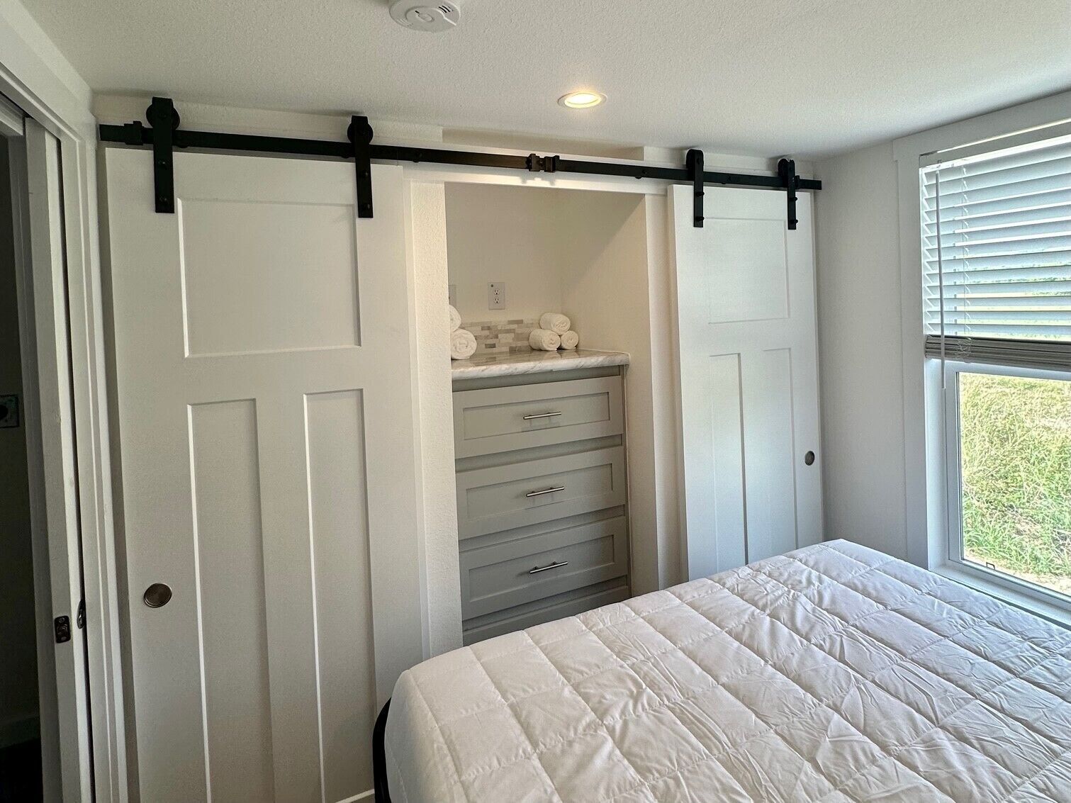 A bedroom with a bed, a dresser, and a closet with a sliding door.