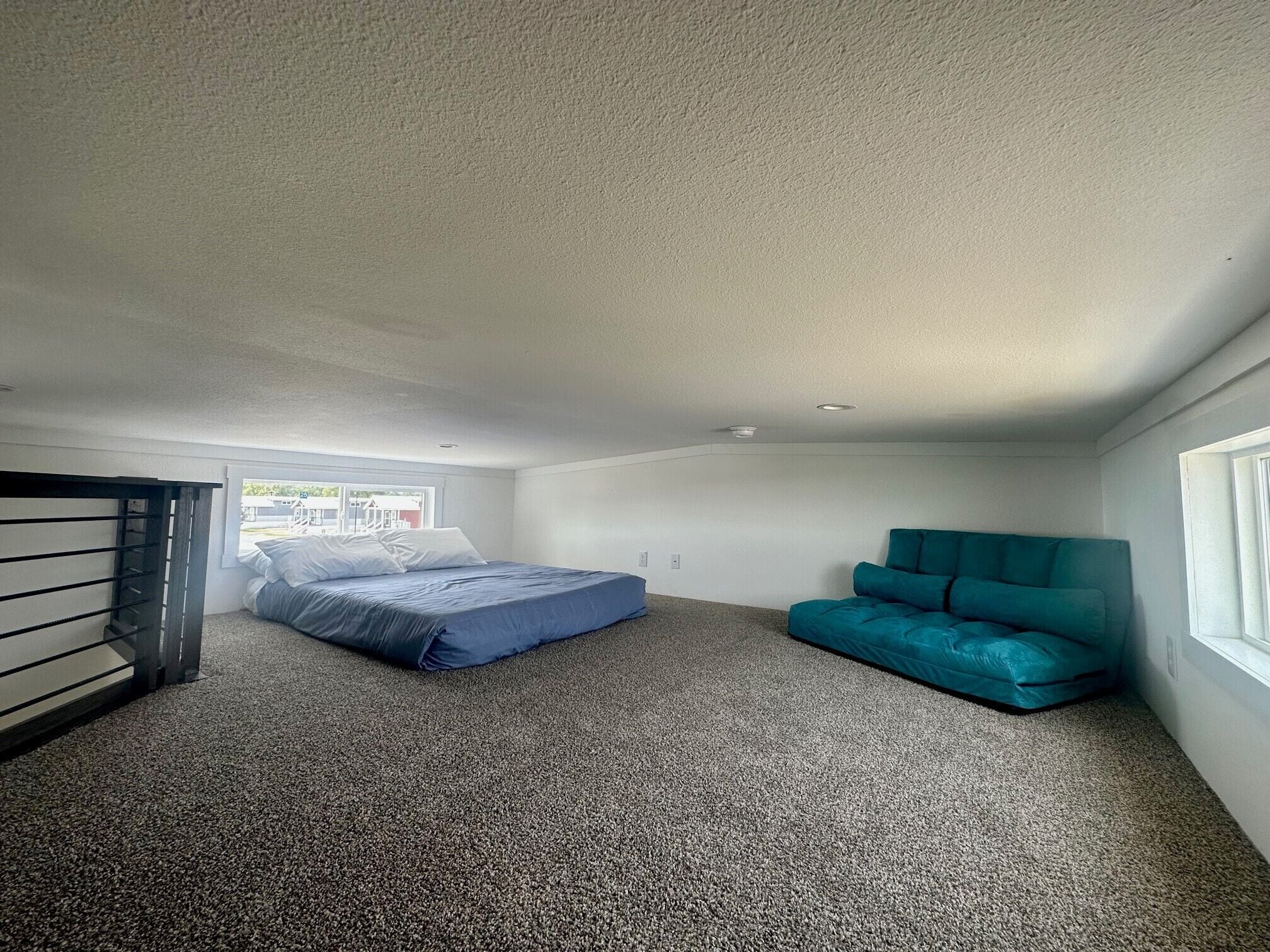 Um quarto com uma cama, um sofá azul-turquesa e uma janela.