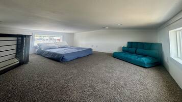 Um quarto com uma cama, um sofá azul-turquesa e uma janela.