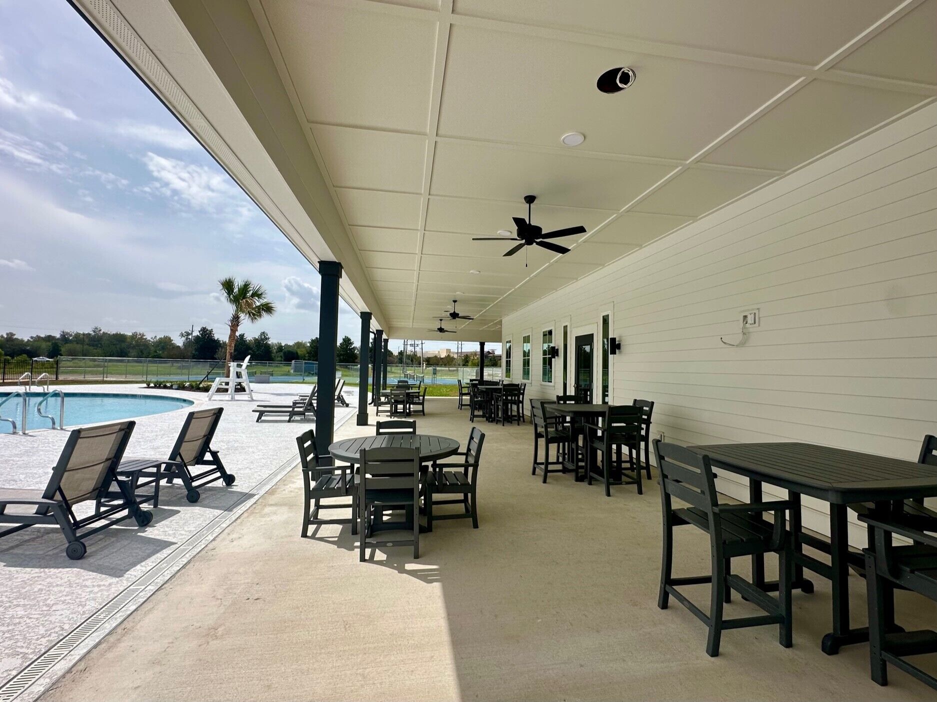 A covered patio area with outdoor seating, a pool, and a view of the surrounding landscape.