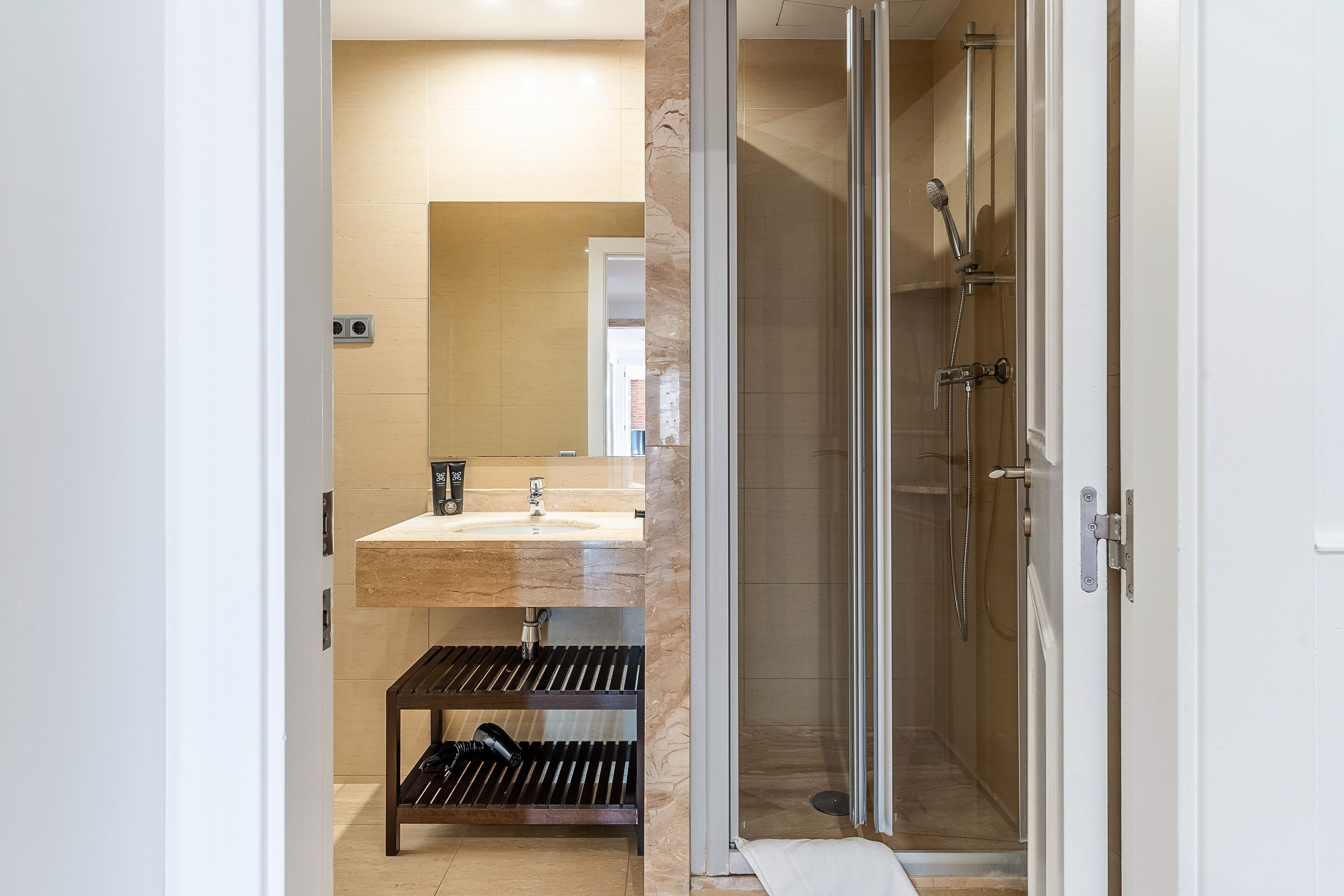 Une salle de bain moderne avec une douche à parois de verre, un mur recouvert de carreaux de marbre et un banc en bois.