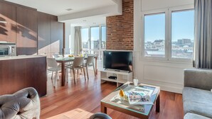 A modern living room with a TV, a glass coffee table, and a sofa. There is a dining area with chairs and a table. - Enjoybcn Fira Apartment (Barcelona)
