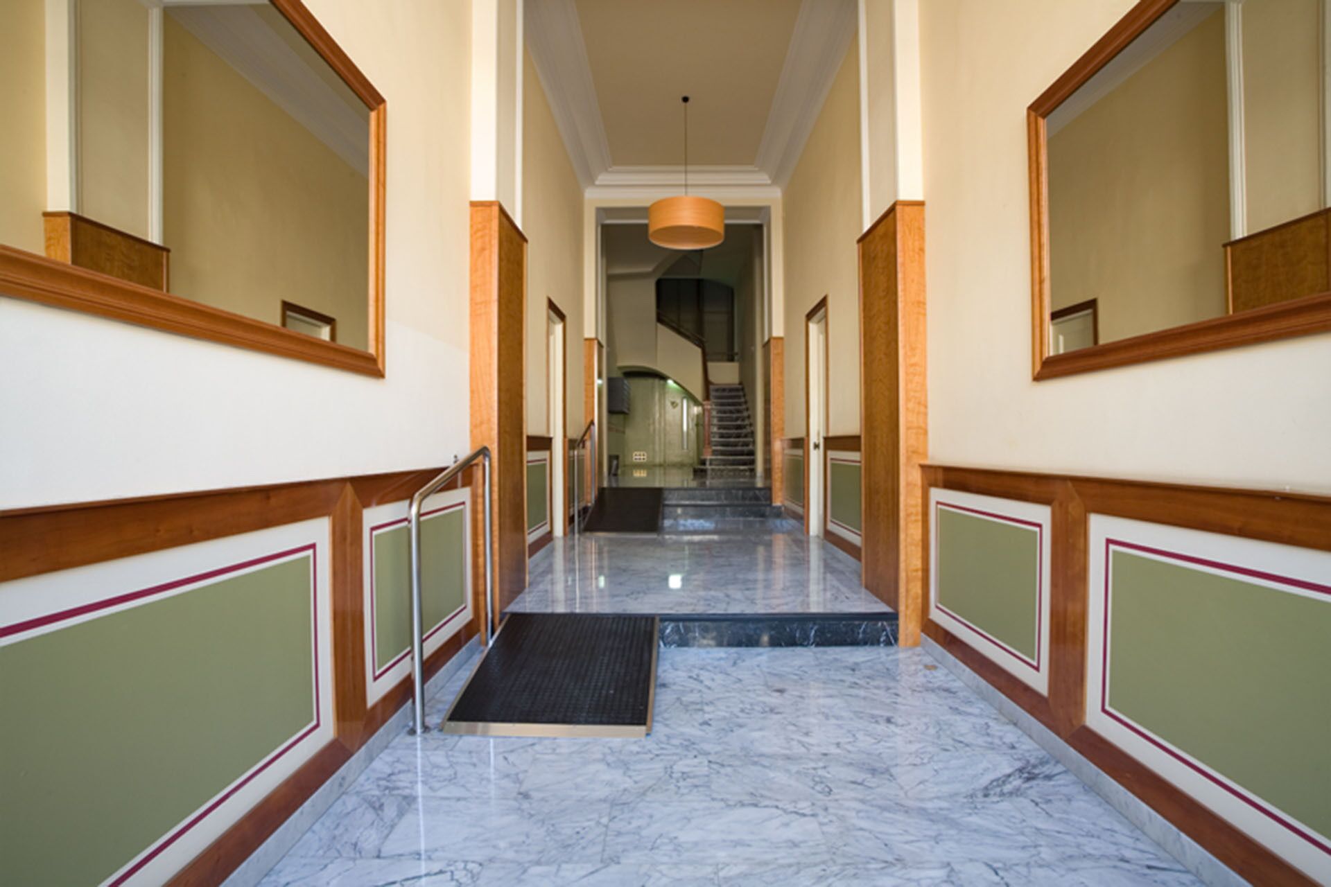 A marble-floored hallway with wooden paneling and a black doormat at the entrance.
