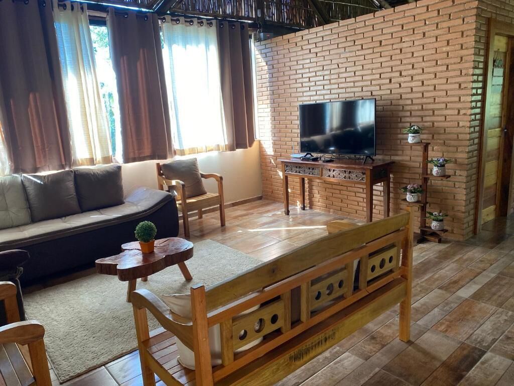 Olohuone, jossa on tiiliseinä, sohva, televisio ja puinen penkki.