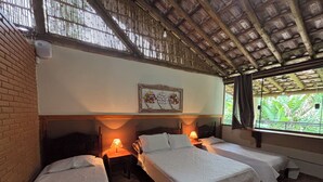 Une chambre avec deux lits simples, un plancher en bois, un mur en briques et une fenêtre donnant sur un paysage verdoyant.