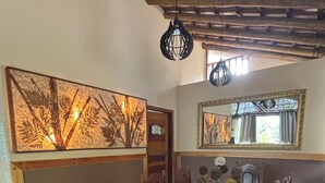 Un coin repas avec une table et des chaises en bois, un panneau décoratif au mur et un miroir au-dessus de la table.