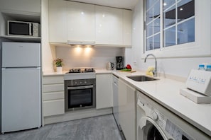 A modern kitchen with a built-in microwave, stove, oven, and dishwasher. - Bright Eixample Flat with Private Terrace Arenas P (Barcelona)