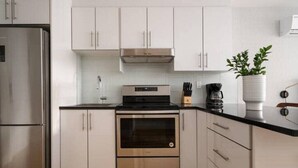 Una cocina moderna con electrodomésticos de acero inoxidable, armarios blancos y piso de madera.