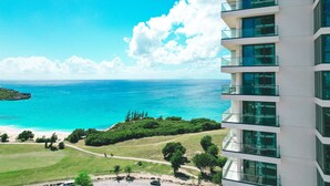 Un immeuble de grande hauteur doté de nombreux balcons donnant sur une plage et l’océan.