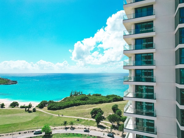 A high-rise building with multiple balconies overlooking a beach and ocean.