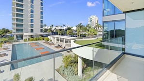 A modern hotel with a swimming pool, lounge chairs, and a view of surrounding buildings. - B-102 Stunning ocean view unit (Cupecoy)