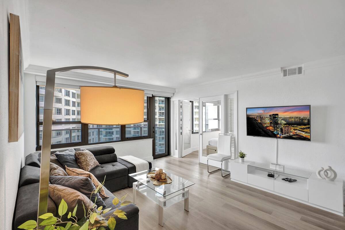 Uma sala de estar moderna com um sofá, mesa de centro e uma TV fixada na parede.