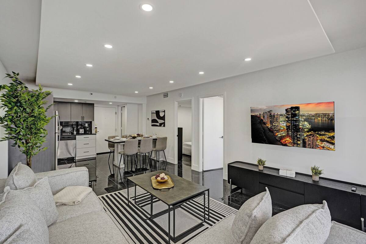 Uma sala de estar moderna com um sofá, uma mesa de centro e um espaço de jantar com cadeiras e uma mesa.