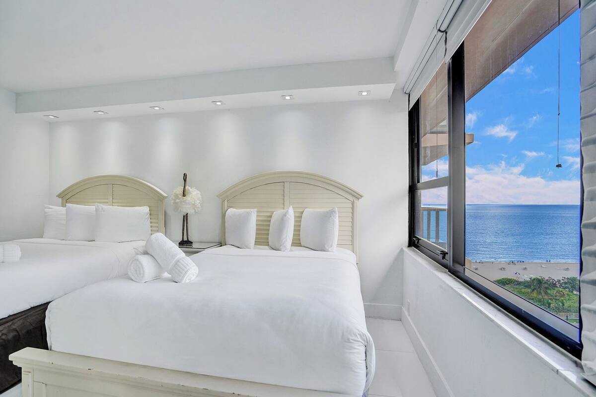 Um quarto moderno com uma cama grande, uma mesinha de cabeceira e vista para o oceano.