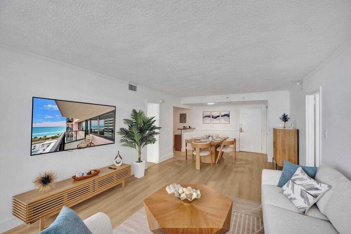 Uma sala de estar moderna com uma mesa de centro de madeira, um sofá e um espaço de jantar com uma mesa e cadeiras de madeira.