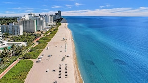 A coastal cityscape with a long sandy beach, high-rise buildings, and clear blue waters. - Alexander Hotel (Miami Beach)