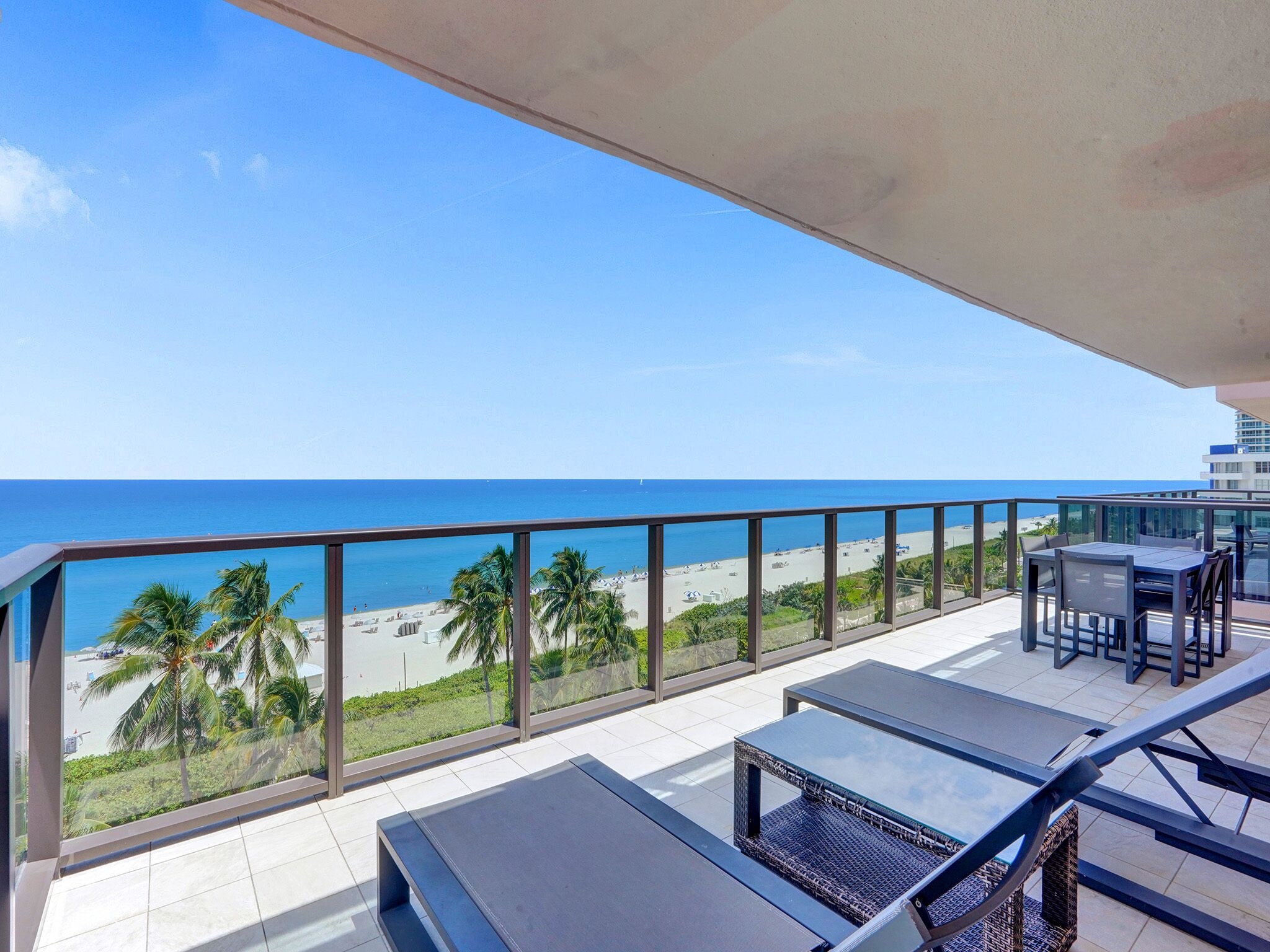 A balcony with a view of the beach and ocean.