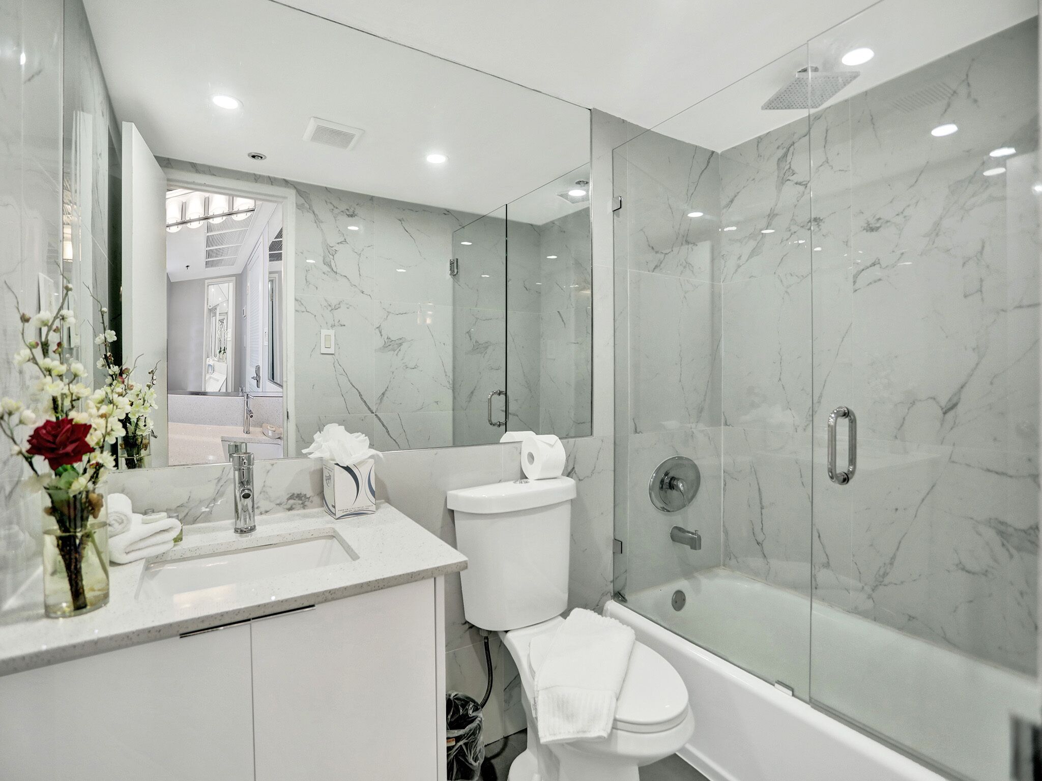 Une salle de bain moderne avec une douche en marbre, des toilettes et un lavabo avec un miroir.