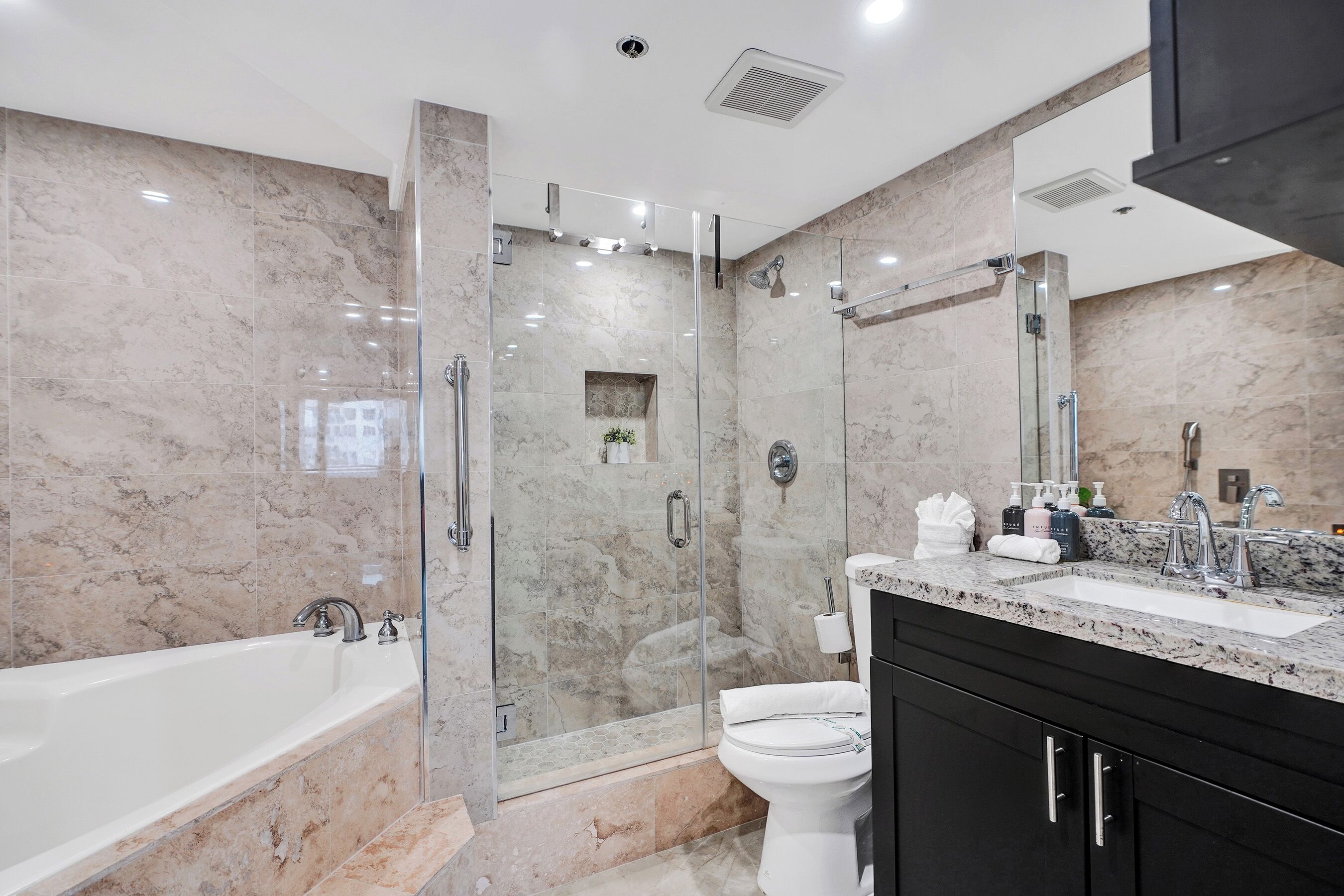 A modern bathroom with a glass-enclosed shower, a freestanding bathtub, a toilet, and a vanity with a sink.