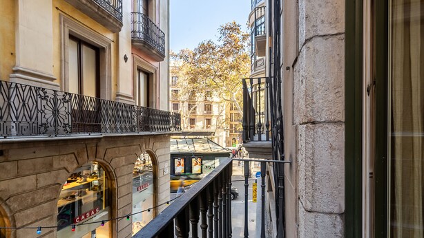 A narrow street with buildings on either side, featuring balconies with wrought iron railings and a storefront with a sign that reads "CASAS." - Enjoybcn Tallers Apartment (Barcelona)