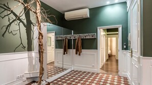 A hallway with a geometric patterned floor, a mirror with a wooden frame, and a tree sculpture. - Enjoybcn Tallers Apartment (Barcelona)