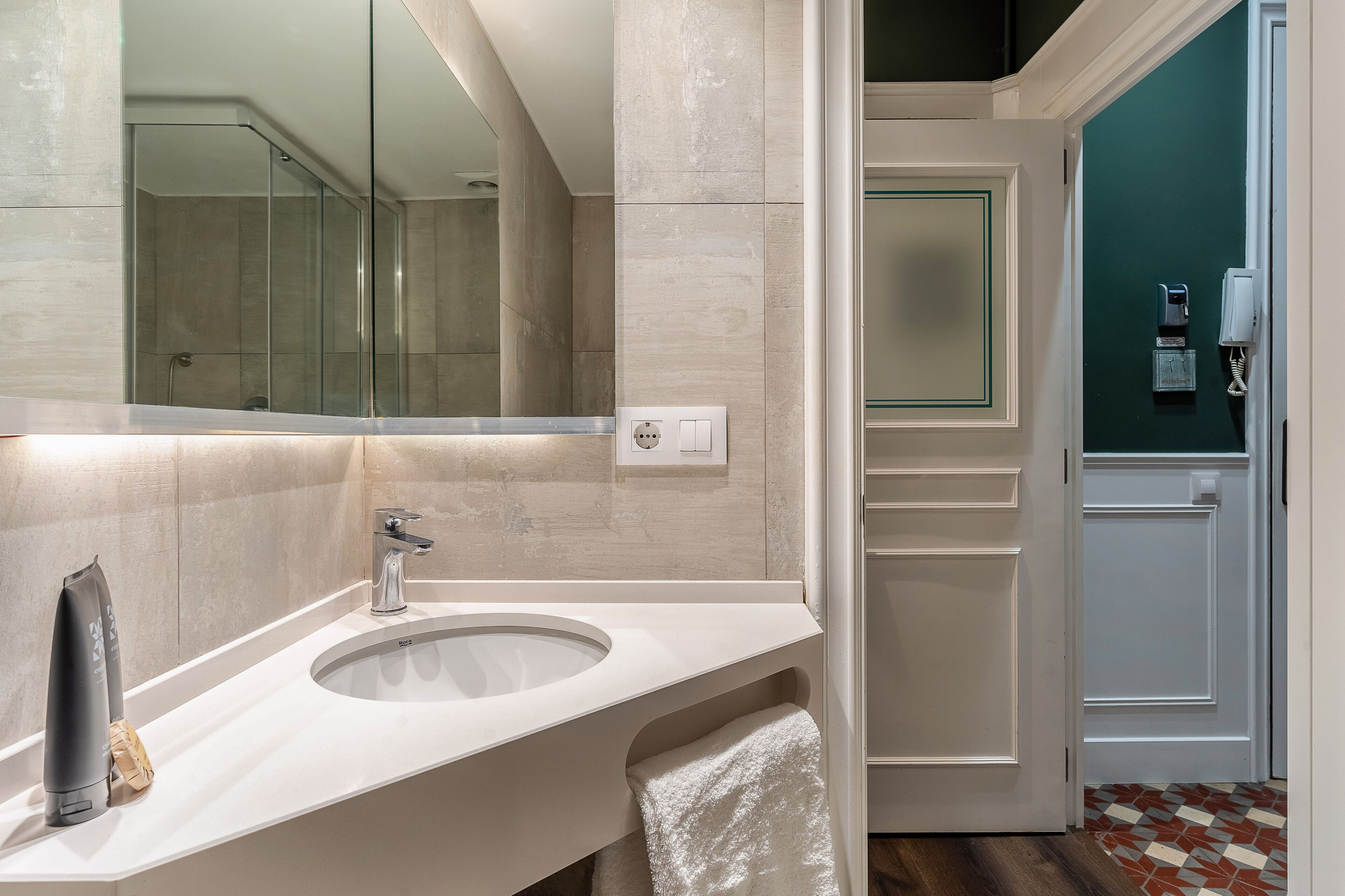 Un baño moderno con un espejo grande, un lavamanos y un perchero para toallas.