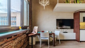 A modern kitchen with a flat-screen TV, a dining area with two chairs, and a large window with a view of buildings. - Enjoybcn Plaza Catalunya Apartment (Barcelona)