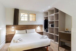A hotel room with a bed, bedside lamps, a wardrobe, and a window with curtains. - Enjoybcn Plaza Catalunya Apartment (Barcelona)