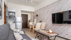 En moderne stue med en grå sofa, et træbord og et tv ophængt på en marmorvæg.