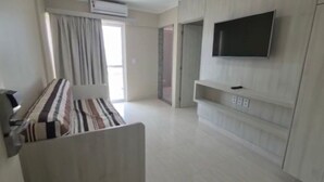 A modern hotel room with a bed, a TV mounted on the wall, and a sliding door leading to a balcony. - Piazza diRoma Acesso Acqua Park (Caldas Novas)