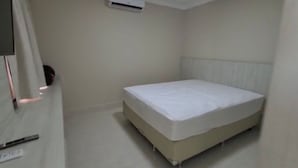 A small, clean room with a single bed, a radiator, and a wall-mounted air conditioner. - Piazza diRoma Acesso Acqua Park (Caldas Novas)