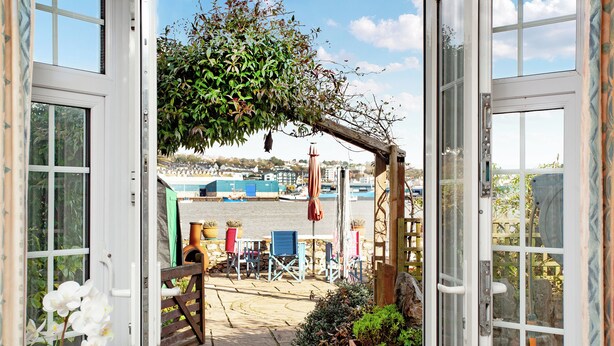 Un'apertura che dà su un patio con vista sul porto, arredi esterni e piante in vaso.