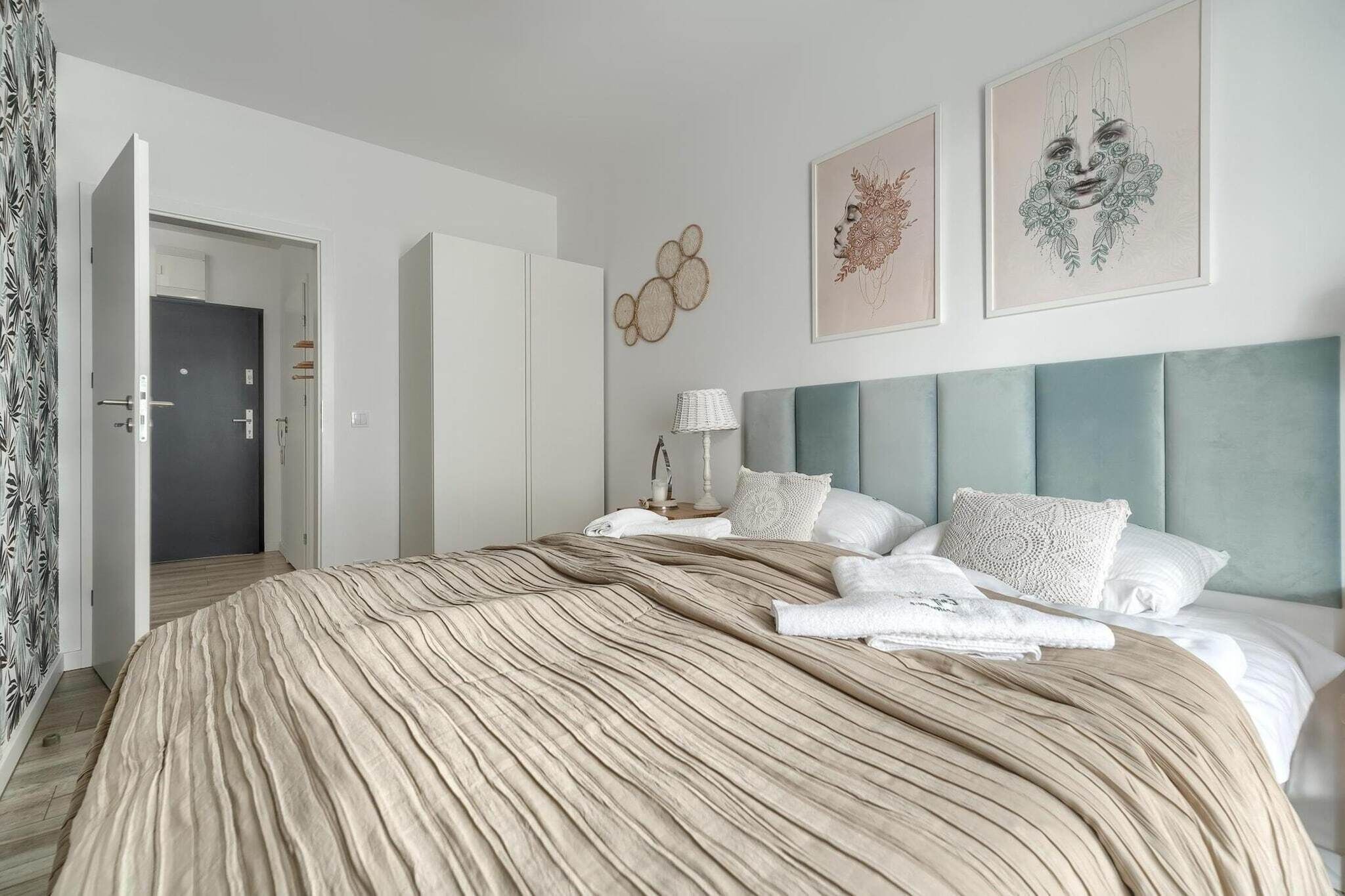 Een moderne hotelkamer met een groot bed, een grijze hoofdbord en kunstwerken aan de muur.