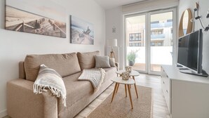 A modern living room with a sofa, a television, and artwork on the wall. - Apartment in Rewal near Baltic Sea Beach (Rewal)