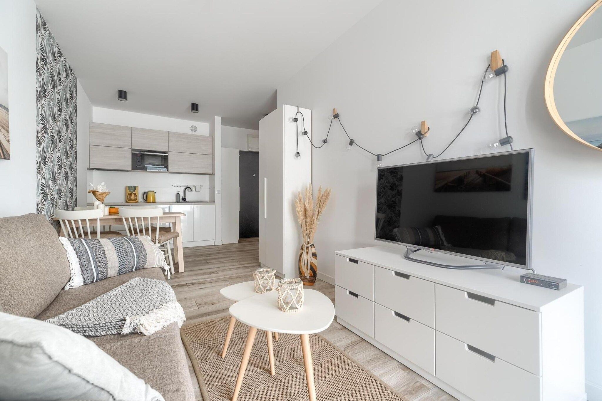 A modern living room with a sofa, coffee table, TV, and a kitchen in the background.