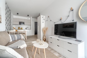 A modern living room with a sofa, coffee table, TV, and a kitchen in the background. - Apartment in Rewal near Baltic Sea Beach (Rewal)