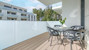 A modern outdoor balcony with a wooden floor, a round table, and two chairs. - Apartment in Rewal near Baltic Sea Beach (Rewal)