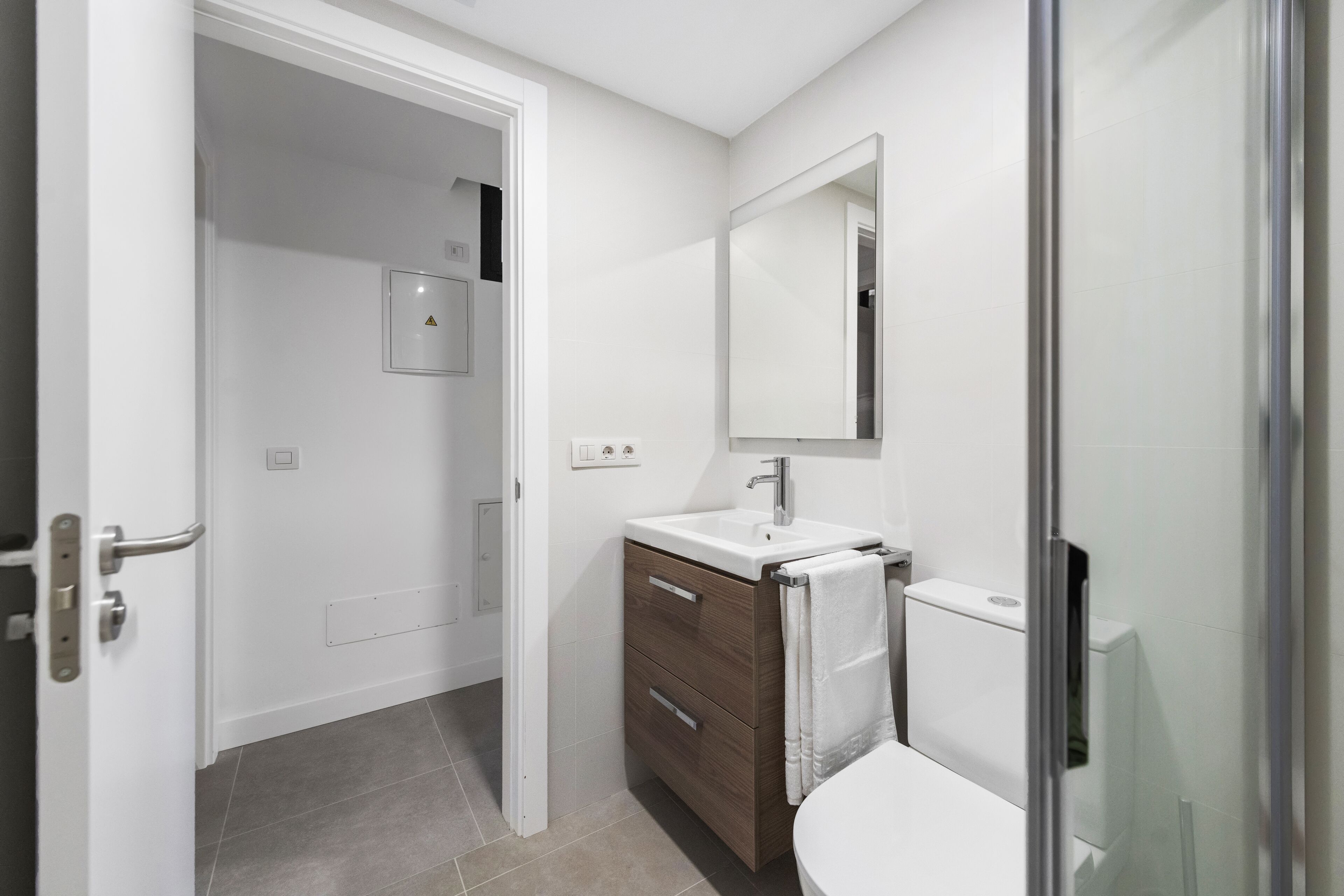Une salle de bain avec un lavabo blanc, un meuble en bois et une cabine de douche en verre.