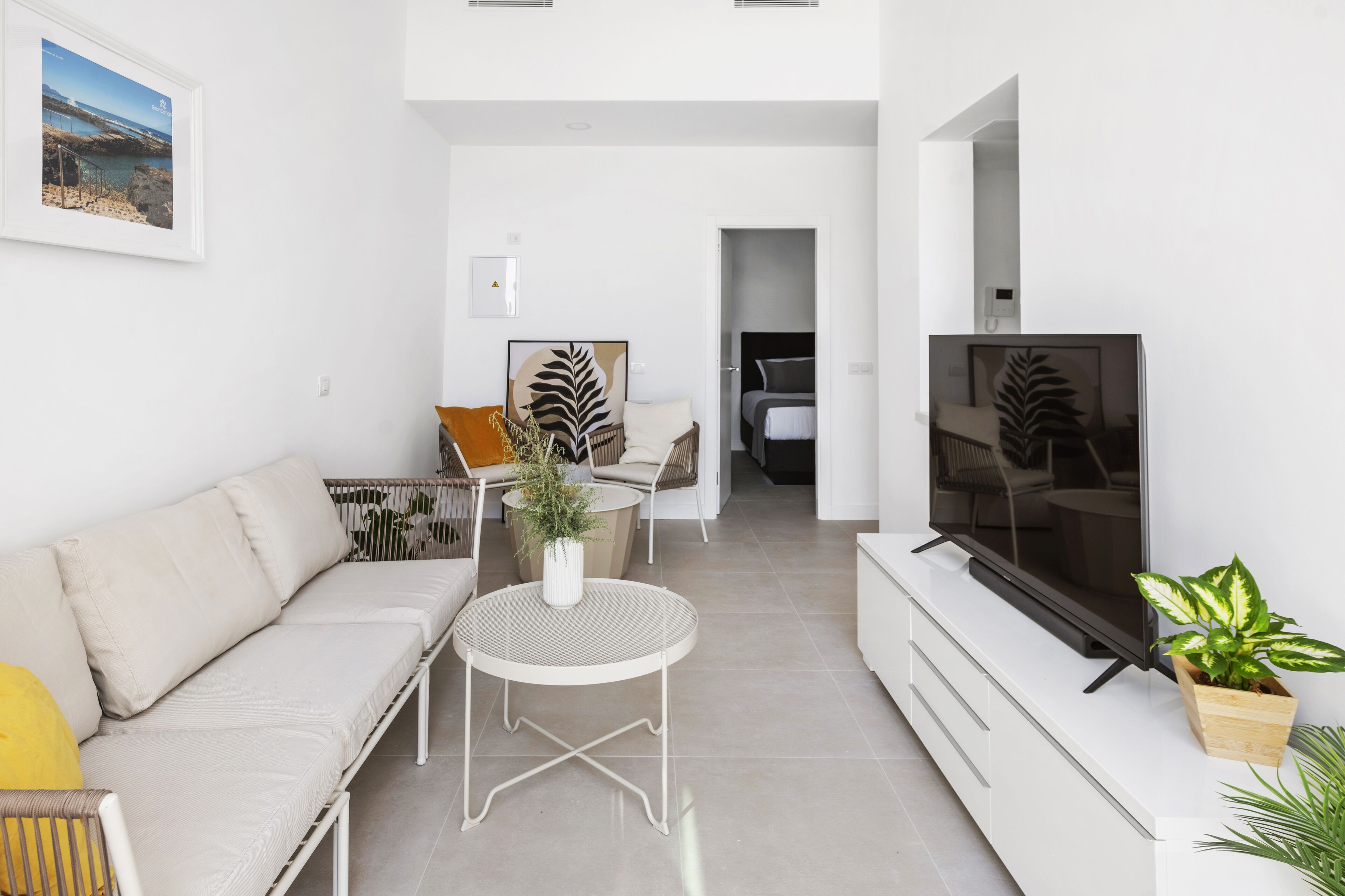 A modern living room with a sofa, a round table, a TV, and a plant.
