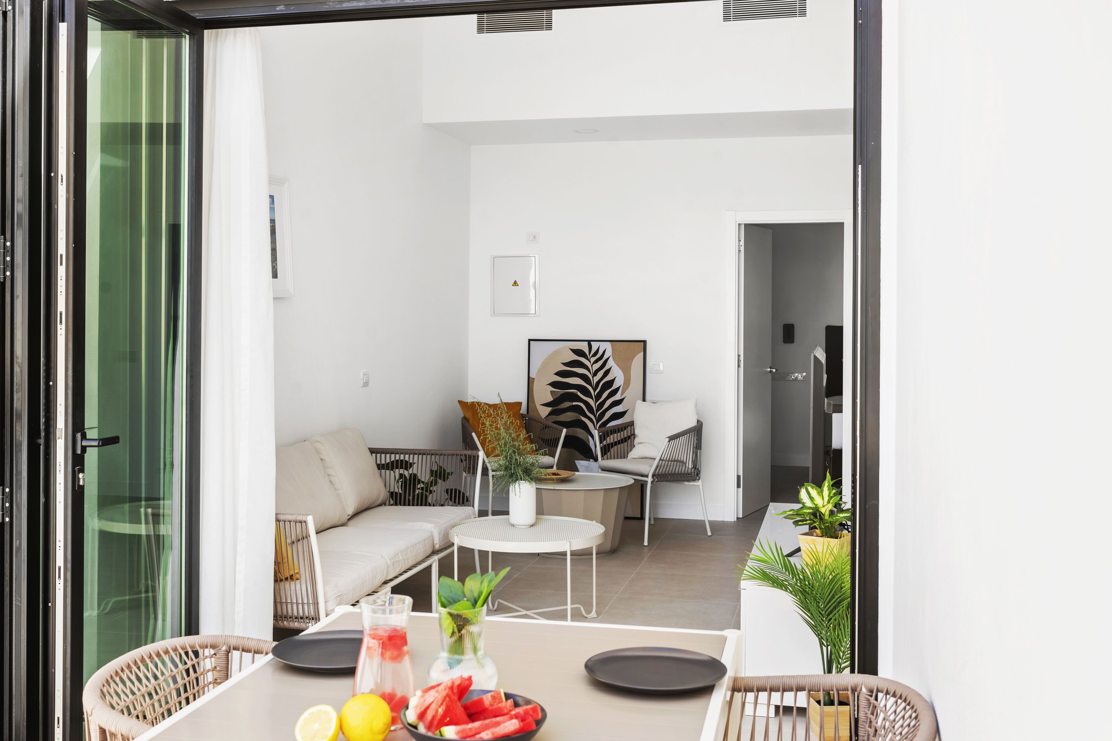 Un salon moderne avec un canapé, une table basse ronde et une table à manger, ainsi que de l’assiette et un vase de fleurs.