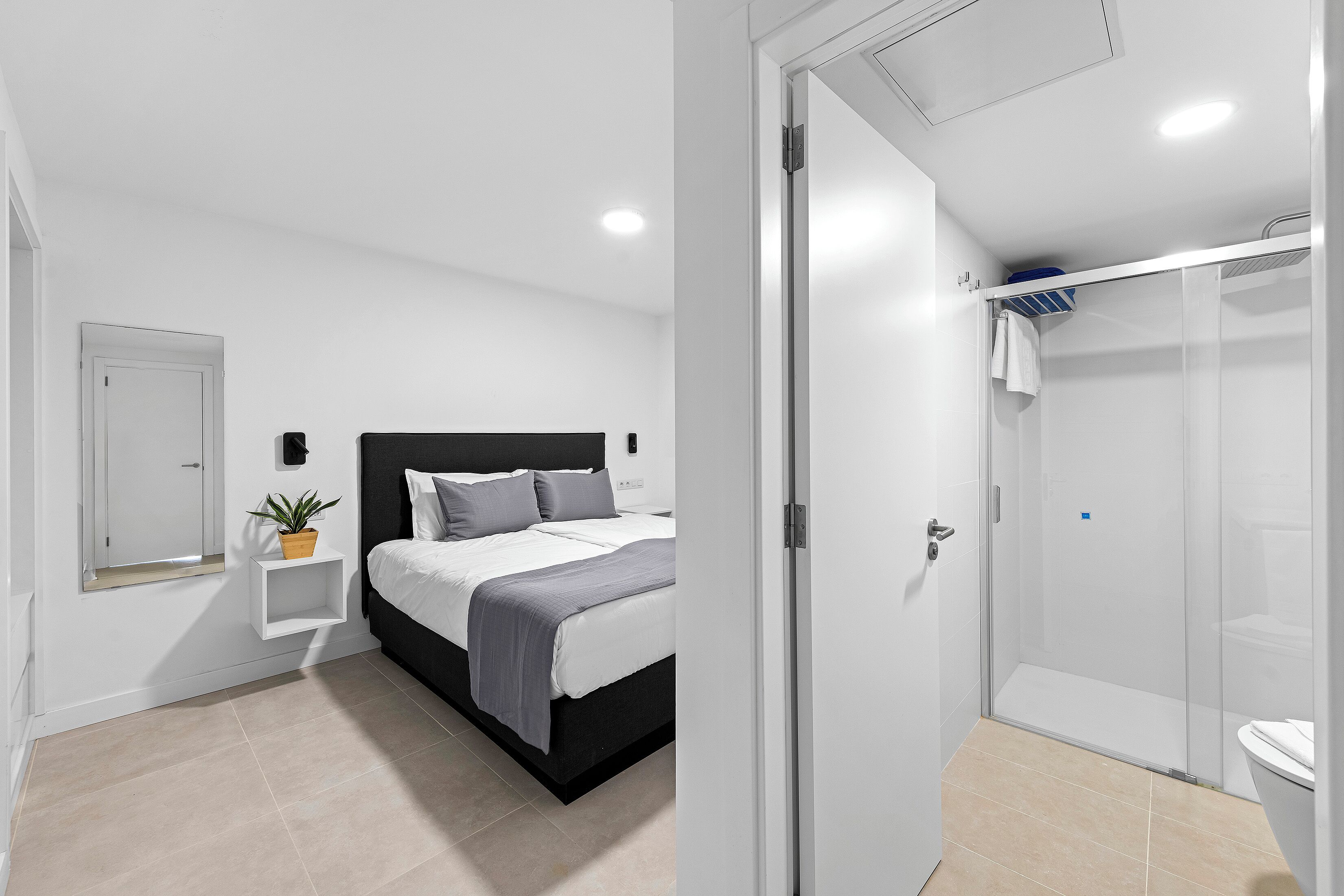 Un dormitorio moderno con cama, mesita de noche y una planta en maceta.