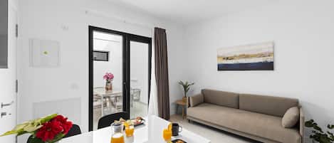 A modern living room with a sofa, dining table, and a painting on the wall.