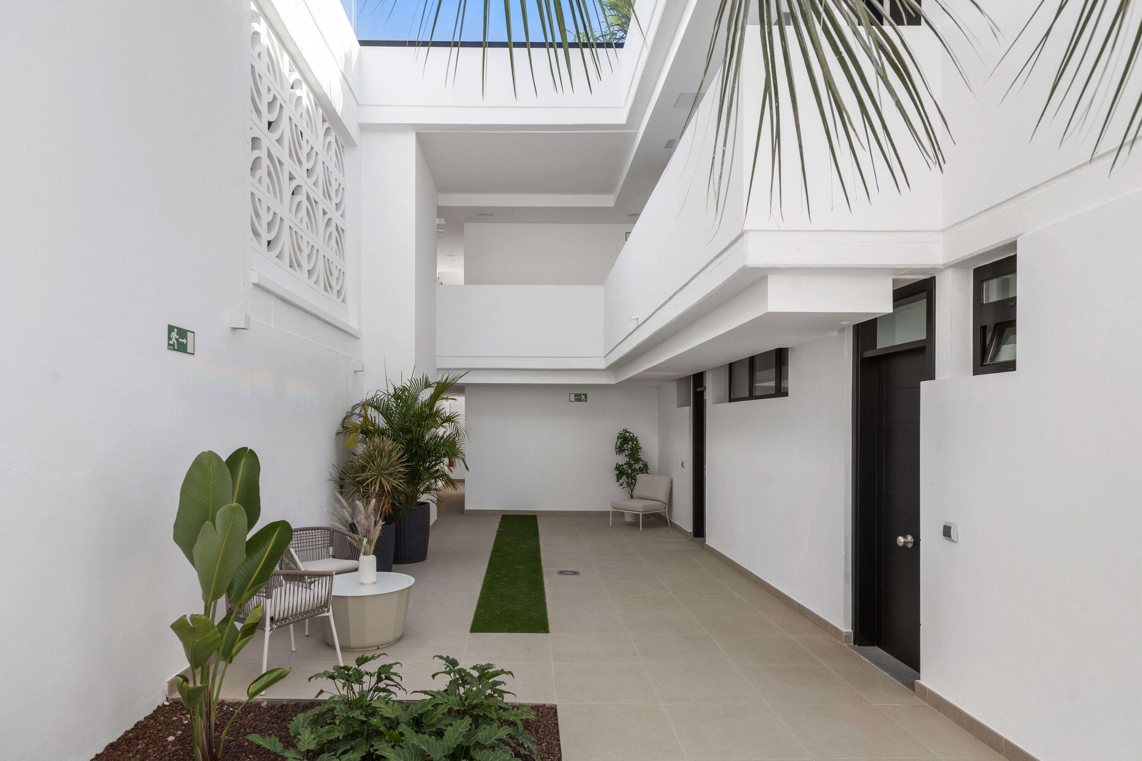 A modern interior with a central green carpet, white walls, and a ceiling with a geometric pattern.